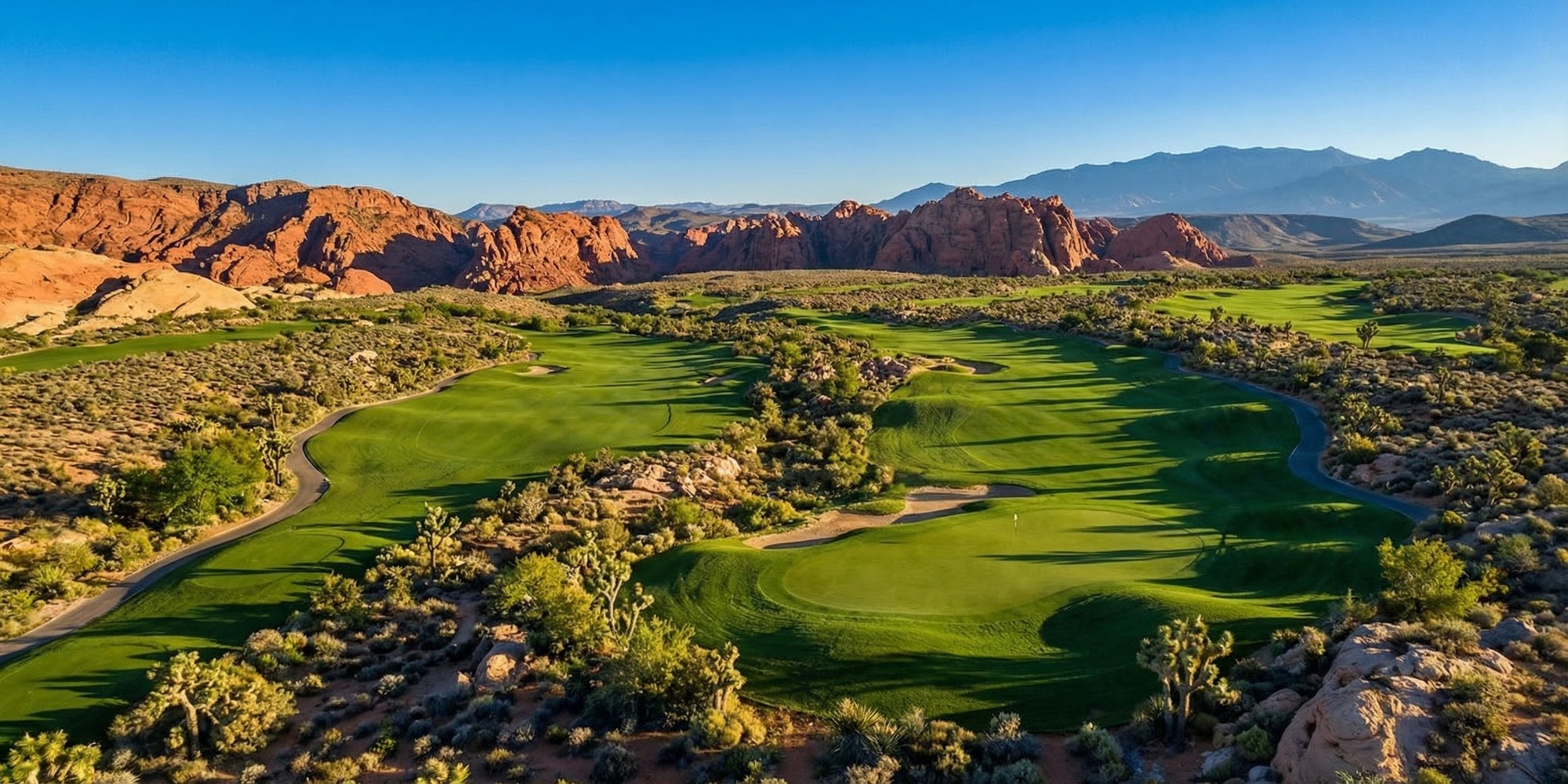 Aerial view of Angel Park Mountain Course fairways winding through Nevada desert with Red Rock Canyon formations in background