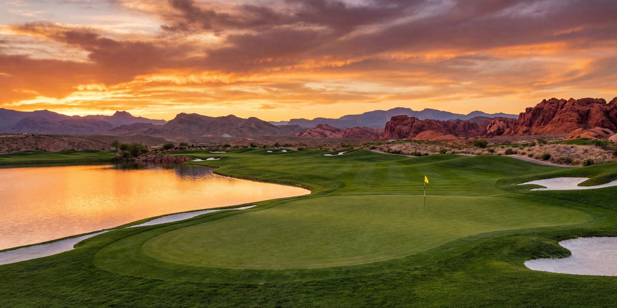 Championship 18th green at TPC Summerlin with lake left, lush bentgrass, and Nevada desert mountain backdrop at golden hour